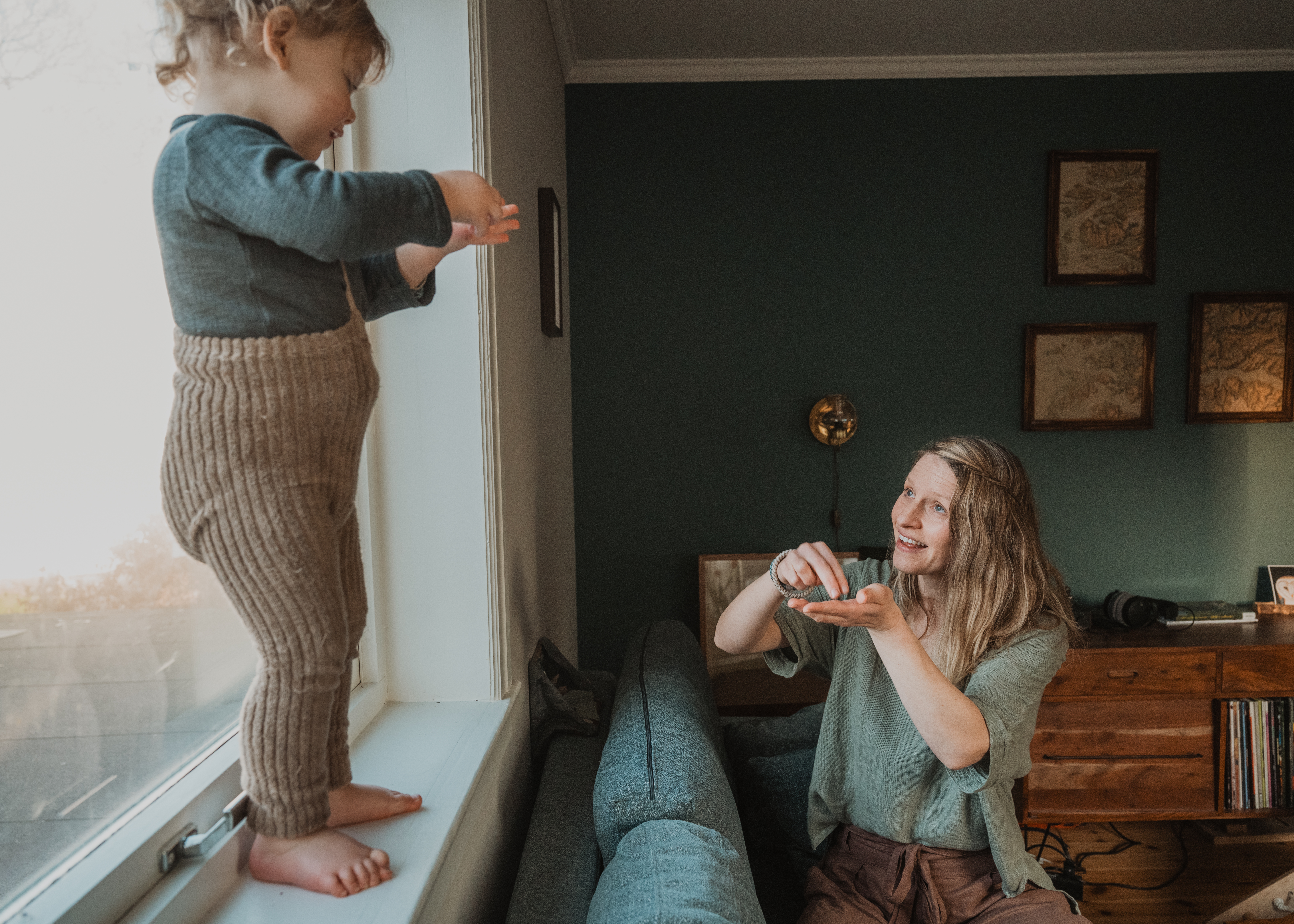 A baby looking intently at their parent's hands.